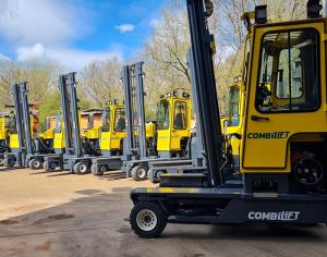 Several CombiLifts lined up, shining bright yellow in the sun