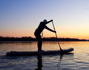 A person on a paddleboard with a sunset in the background