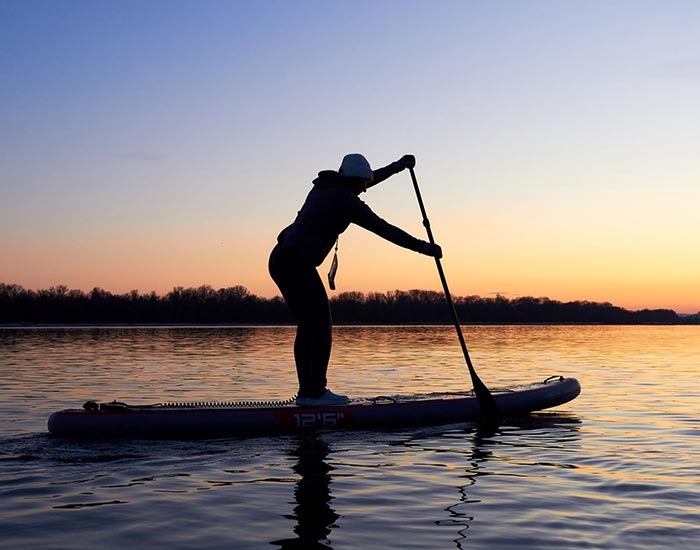 Sandra - AJN A person on a paddleboard with a sunset in the background