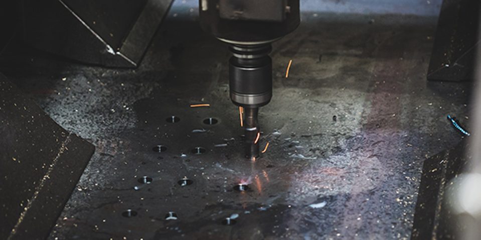 CNC Drilling - AJN Steelstock An AJN Steelstock CNC drilling machine working on making one of many holes in a steel beam with sparks flying out of the hole