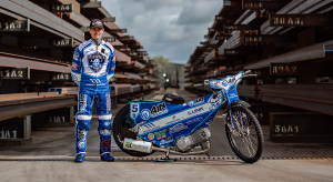 Speedway rider Lewis Kerr standing next to his bike while standing in a steel yard
